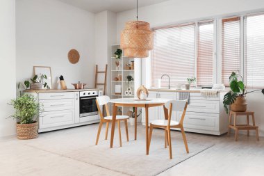 Mutfağın içinde yemek masası, tezgah ve bitkiler var.