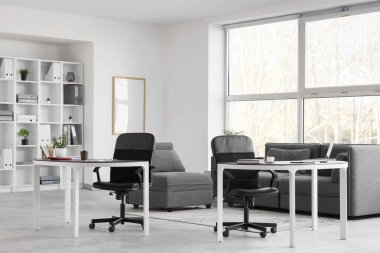 Masaları ve raf ünitesi olan ofis içi