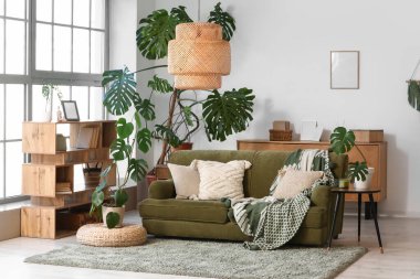 Oturma odasının içinde rahat bir kanepe ve Monstera bitkileri var.