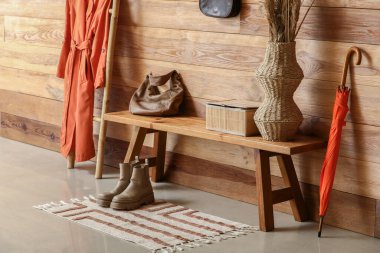 Çantalı bank, vazodaki otlar ve koridordaki merdivende asılı duran palto.