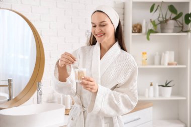 Banyoda pamuklu tomurcukları olan genç bir kadın.