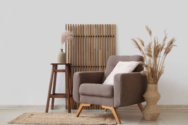 Koltuk, ekran ve otlar beyaz duvarın yanındaki vazolarda.