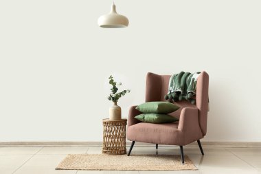 Koltuk, ekoseli yastıklar ve okaliptüs dalları odadaki sehpanın üstündeki vazoda.