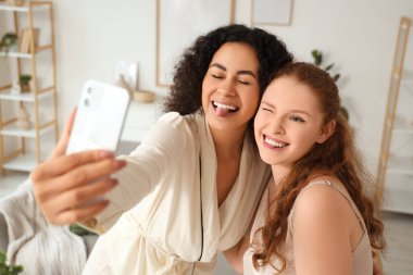 Cep telefonlu güzel, genç bayan arkadaşlar evde selfie çekiyorlar.