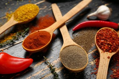 Koyu ahşap arka planda, kaşık dolusu aromatik baharat içeren kompozisyon, yakın plan.