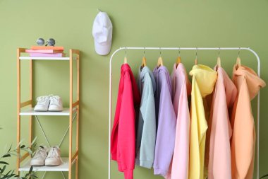 Odada yeşil duvarın yanında giysilerle dizilin.