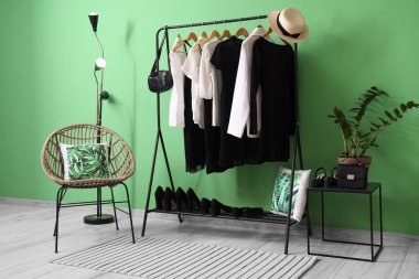 Yeşil duvarın yanında siyah beyaz elbiseli raflar.