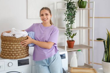 Evde çamaşırları olan genç bir kadın.