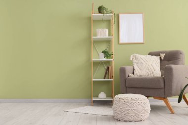 Koltuk, raf ünitesi ve pouf yeşil duvarın yanında.