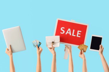 Dizüstü bilgisayarı, tableti, kredi kartı ve mavi arka planda satış işareti olan kadın eller. Kara Cuma indirimi