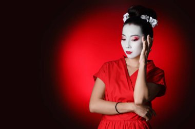 Beautiful young geisha on dark red background clipart