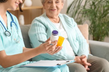 Genç hemşire evde yaşlı bir kadına reçete yazıyor, yakın çekim.