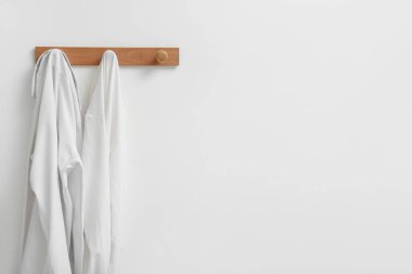 Işık duvarında asılı beyaz gömlekli raflar