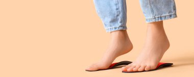 Ortopedik tabanlar üzerinde duran çıplak ayaklı kadın bej arkaplan ve metin için yer var.