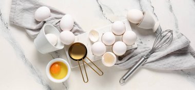 Beyaz arka planda çiğ tavuk yumurtası ve mutfak aletleriyle tutucu ve kase.