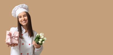 Kadın aşçı laleleri tutuyor ve bej arka planda hediye kutusu ve mesaj için yeri var. Uluslararası Kadınlar Günü kutlamaları