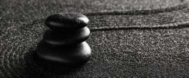 Çizgileri olan siyah kumlar üzerinde taş yığını. Zen kavramı