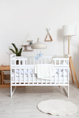 Interior of light children's bedroom with baby crib and shelves