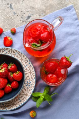 Arkaplanda çilek olan bir bardak ve bir sürahi eritilmiş su.