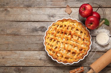 Lezzetli elmalı turta ve ahşap arka planda malzemelerle pişirme yemeği.