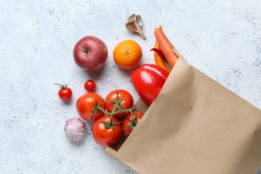 Açık mavi arka planda meyve ve sebzeli kağıt torba.