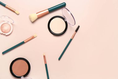 Pembe arka planda makyaj fırçaları ve farklı dekoratif kozmetikler