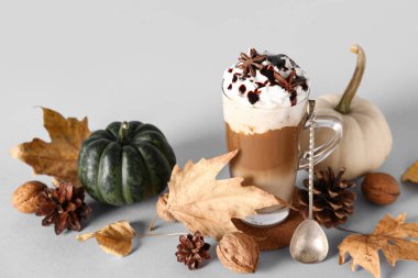 Bir bardak lezzetli balkabaklı latte, yıldız anason ve beyaz arka planda ceviz.