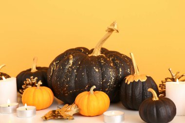 Sarı duvarın yanında balkabakları ve mumlar