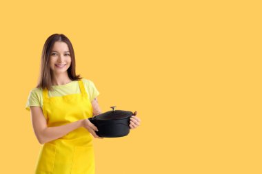 Önlüklü, turuncu arka planda tenceresi olan güzel bir kadın.
