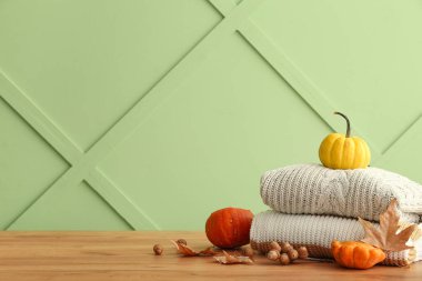 Şık süveter, balkabağı, yapraklar ve ahşap arka planda meşe palamudu yığınıyla sonbahar kompozisyonu