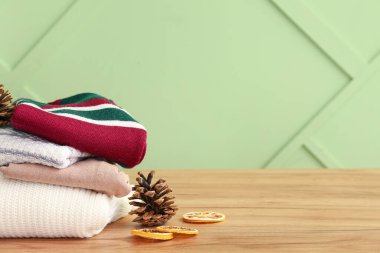 Süslü süveter, kurutulmuş limon ve ahşap masanın üzerinde çam kozalakları olan kompozisyon.