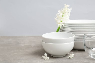 Gri duvarın yanındaki masada güzel sofra takımı ve çiçekler.