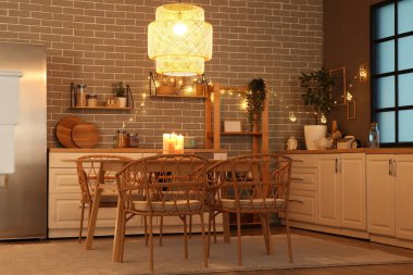 Parlayan lambaları, beyaz tezgahları, buzdolabı ve akşam yemeği masası olan şık bir mutfak.