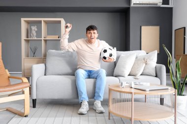 Genç adam TV 'de futbol maçı izliyor.