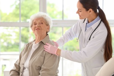 Klinikteki kıdemli hastayı muayene eden kadın doktor.