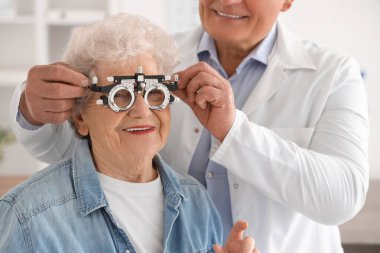 Erkek göz doktoru klinikteki yaşlı kadına dava çerçevesi takıyor, yakın plan.