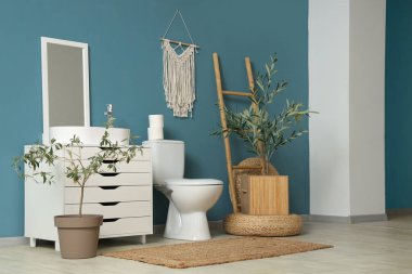 Modern banyo, lavabo, klozet ve dekoratif zeytin ağaçları.