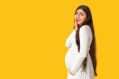 Sarı arka planda hamile bir kadın.