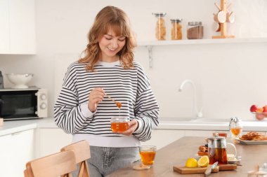 Tatlı ballı genç kadın ve mutfakta bir fincan çay.