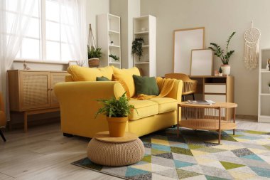 Konforlu kanepe, sehpa, çekmeceler ve oturma odasında sandalyeli bir masa.