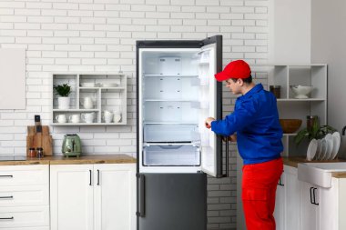 Mutfaktaki buzdolabını tamir eden erkek işçi.