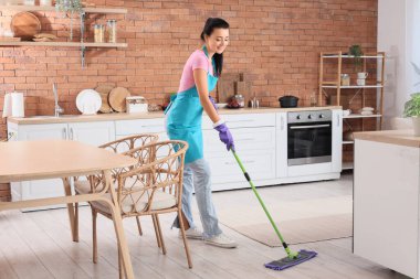 Mutfakta yerleri paspaslayan genç kadın.