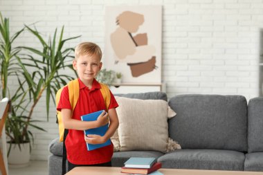 Sırt çantası ve kitabı olan sevimli bir çocuk.