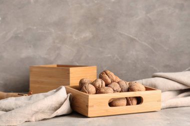 Gri arka planda lezzetli cevizler olan ahşap kutu.