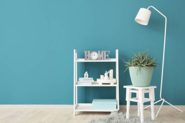 Oturma odasının içinde lamba, raf ve bitki var.