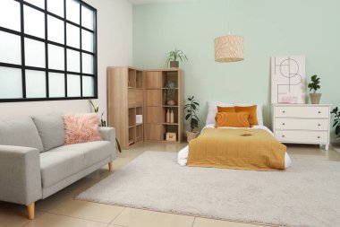 İçinde yatak, kanepe ve bitkiler olan bir gencin odası.