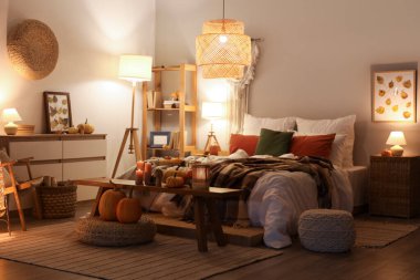 Sonbahar süslemeleri ve akşamları mumları olan şık bir yatak odası.