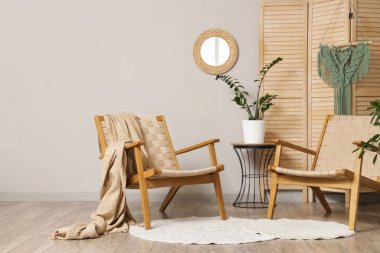 Ayna, katlanan ekran ve koltuklu aydınlık oturma odasının içi