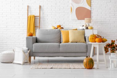 Sonbahar dekoru, kanepesi ve masası olan aydınlık oturma odasının içinde.