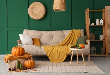 Rahat bir kanepe, puf ve kahve masası. Oturma odasının içinde sonbahar dekoru var.